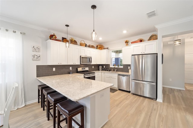 kitchen featuring decorative light fixtures, white cabinets, and appliances with stainless steel finishes