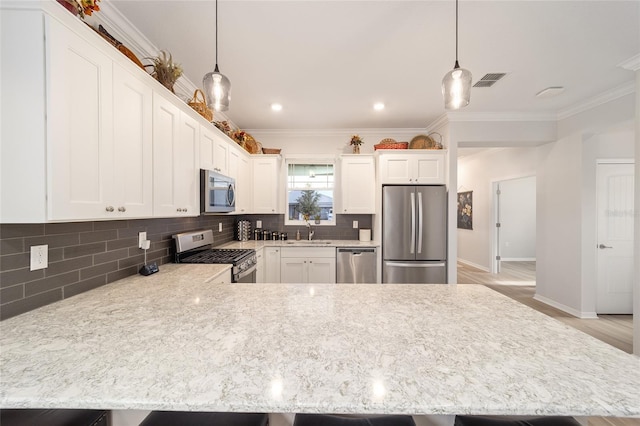 kitchen with white cabinets, appliances with stainless steel finishes, decorative light fixtures, tasteful backsplash, and sink