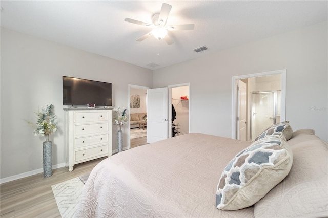 bedroom featuring a spacious closet, light hardwood / wood-style flooring, a closet, and ceiling fan