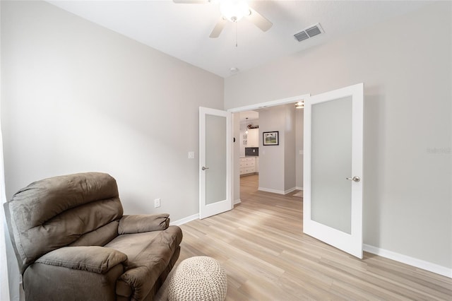 living area with light wood-type flooring, ceiling fan, and french doors