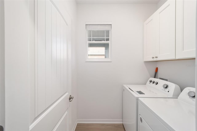 laundry area with washer and dryer, cabinets, and light wood-type flooring