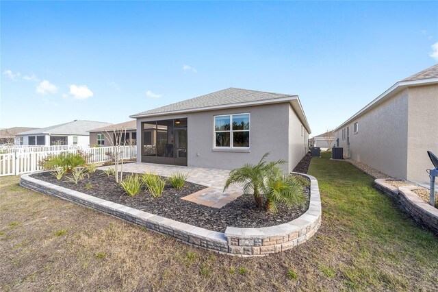 back of property featuring a patio area, a yard, a sunroom, and central AC