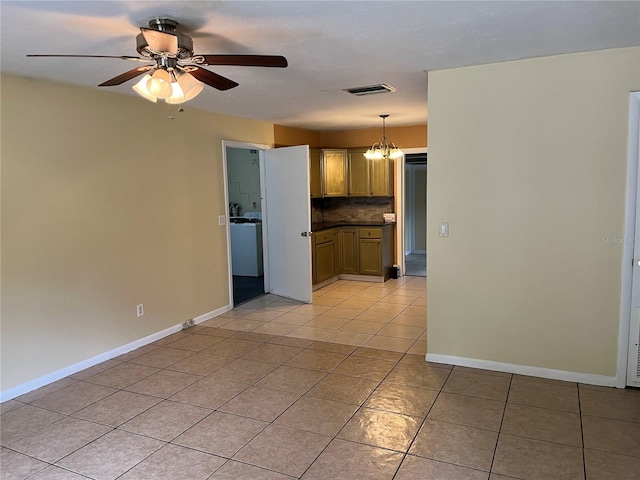 interior space with ceiling fan with notable chandelier, pendant lighting, washer / clothes dryer, backsplash, and light tile patterned floors