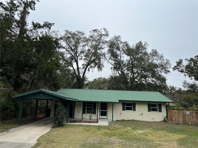 ranch-style house featuring a front lawn, a carport, and covered porch