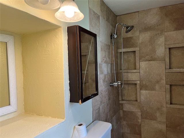 bathroom featuring a tile shower and toilet