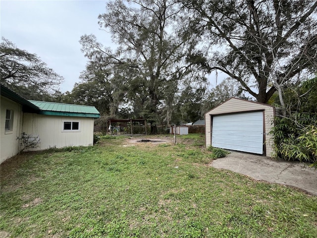 view of yard featuring a garage, a carport, and an outbuilding