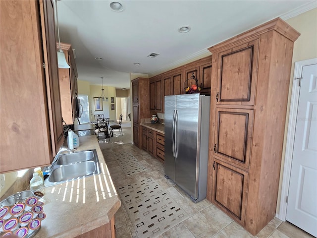 kitchen featuring stainless steel fridge, ornamental molding, sink, light tile patterned floors, and hanging light fixtures