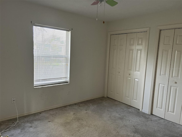 unfurnished bedroom with two closets, ceiling fan, and light carpet