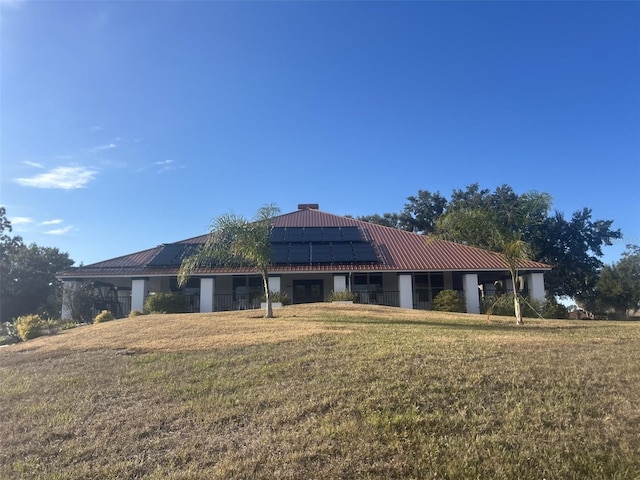 view of front of property featuring a front yard and solar panels