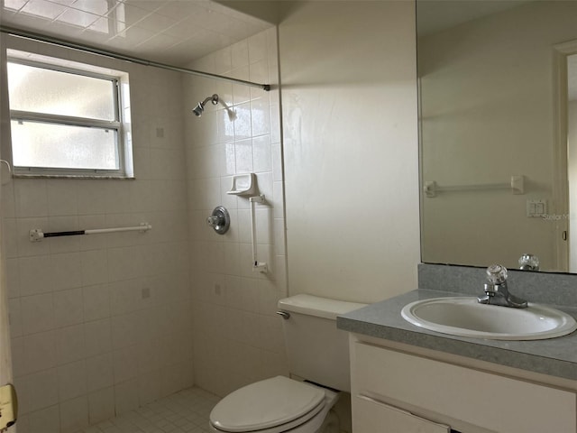 bathroom with a tile shower, vanity, and toilet