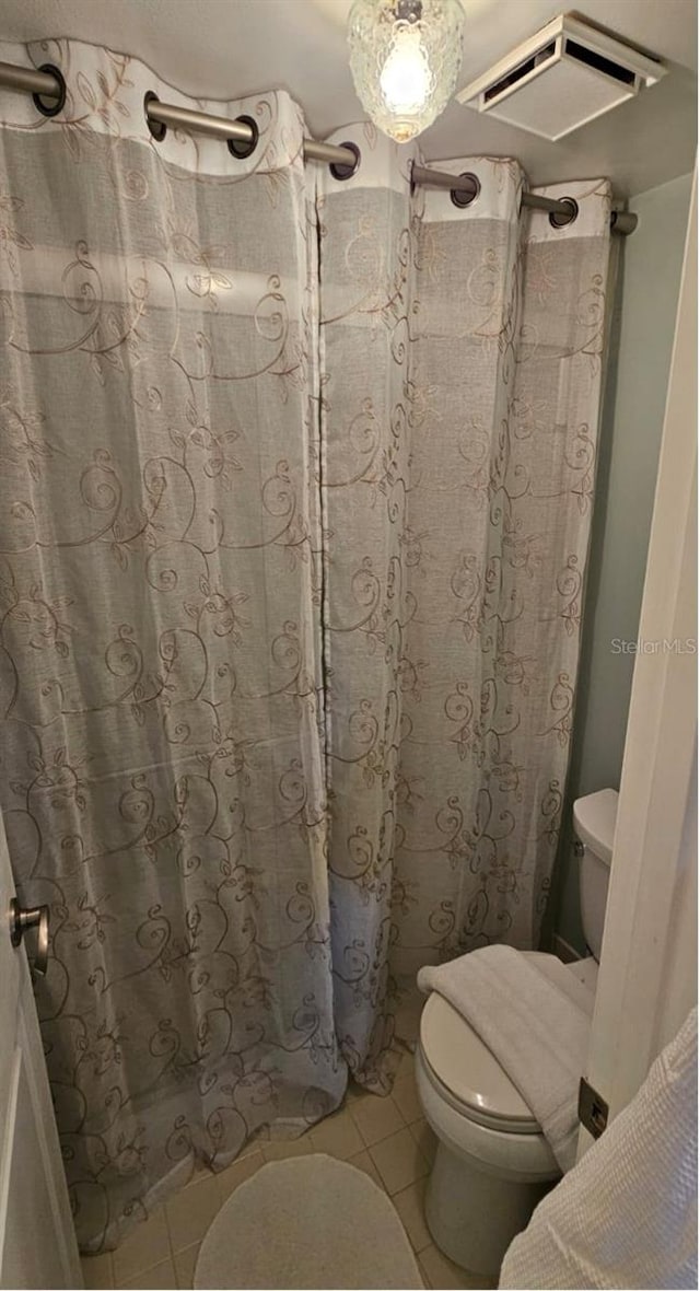 bathroom featuring tile patterned flooring, curtained shower, and toilet