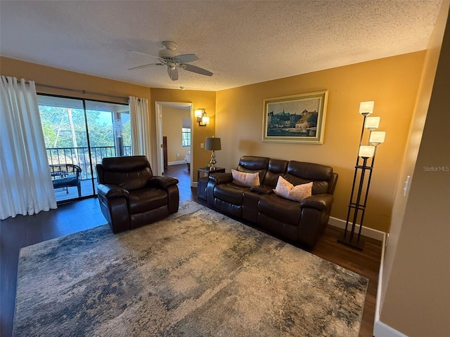 living room with ceiling fan, dark hardwood / wood-style floors, and a textured ceiling