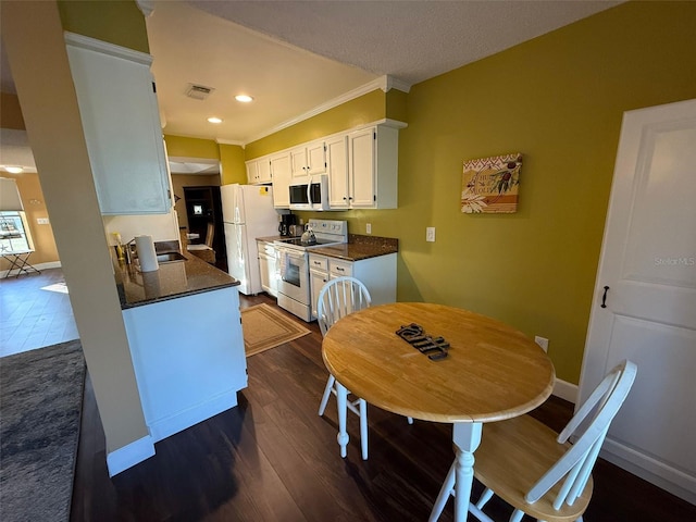 kitchen with crown molding, white appliances, dark hardwood / wood-style flooring, and white cabinets