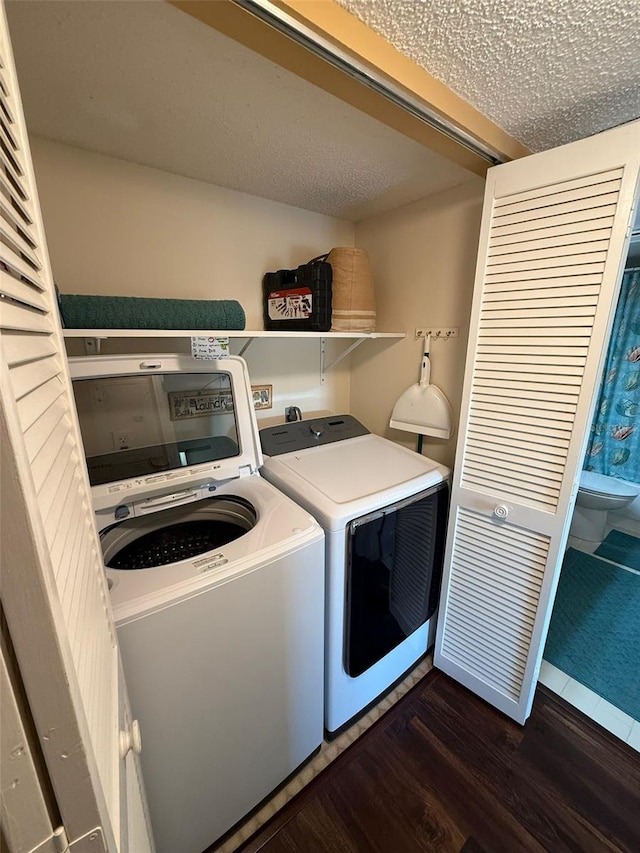 clothes washing area with washer and clothes dryer, a textured ceiling, and dark hardwood / wood-style flooring