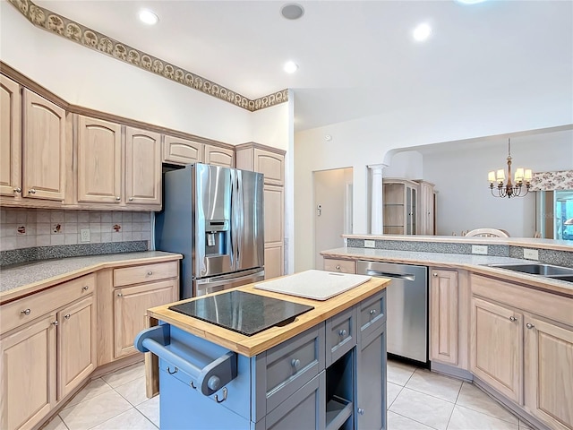 kitchen with a kitchen island, hanging light fixtures, appliances with stainless steel finishes, light brown cabinets, and a chandelier