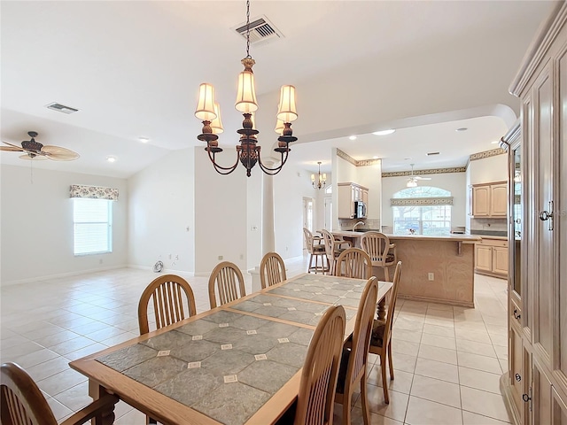 tiled dining room featuring lofted ceiling and ceiling fan with notable chandelier