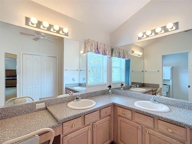 bathroom featuring ceiling fan, toilet, vanity, and vaulted ceiling