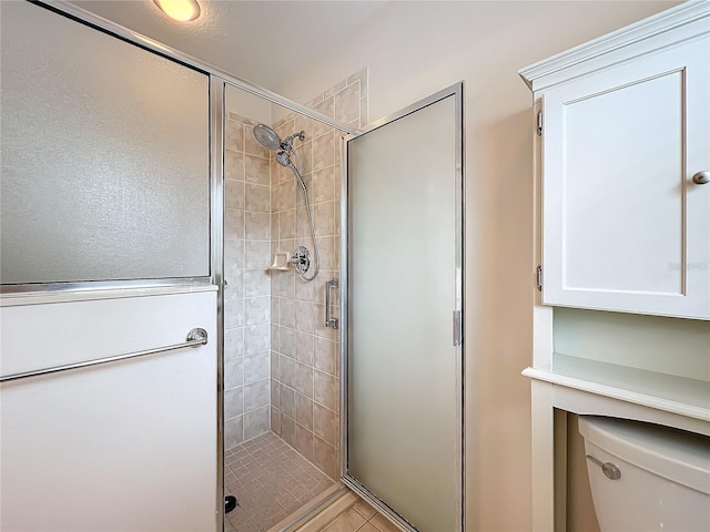 bathroom with toilet, tile patterned floors, and a shower with shower door