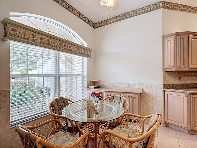 tiled dining space featuring ceiling fan, a healthy amount of sunlight, and tile walls