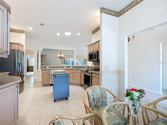 kitchen with appliances with stainless steel finishes, a center island, light brown cabinets, decorative columns, and light tile patterned floors