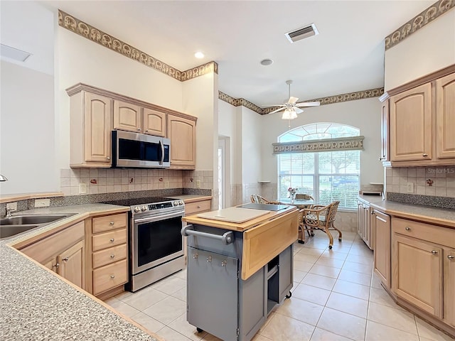 kitchen with ceiling fan, sink, light tile patterned flooring, stainless steel appliances, and light brown cabinetry