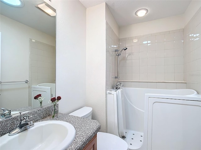 bathroom featuring toilet, vanity, and a tile shower