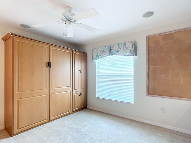 unfurnished bedroom with ceiling fan, light colored carpet, and a closet