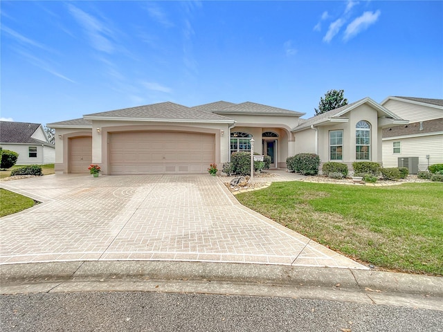 view of front of home featuring central AC, a garage, and a front yard