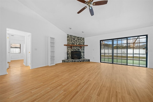 unfurnished living room with ceiling fan, a fireplace, vaulted ceiling, and light wood-type flooring