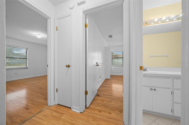 corridor featuring light hardwood / wood-style flooring, plenty of natural light, and sink