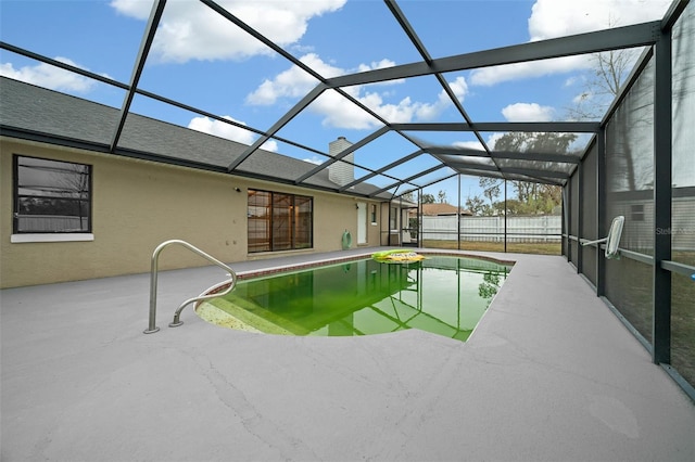 view of pool with glass enclosure and a patio area