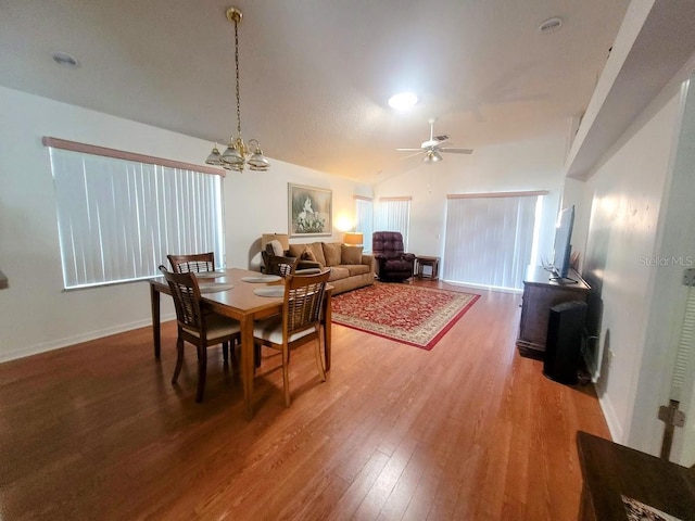 dining room featuring ceiling fan with notable chandelier, hardwood / wood-style flooring, and lofted ceiling