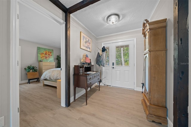 entryway with a textured ceiling, light hardwood / wood-style flooring, and crown molding