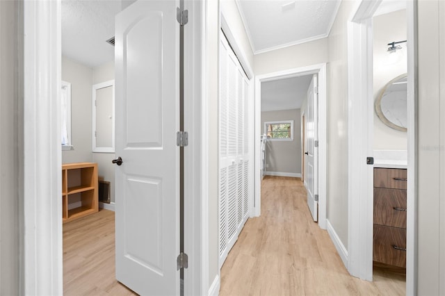 hall featuring ornamental molding, a textured ceiling, and light hardwood / wood-style floors