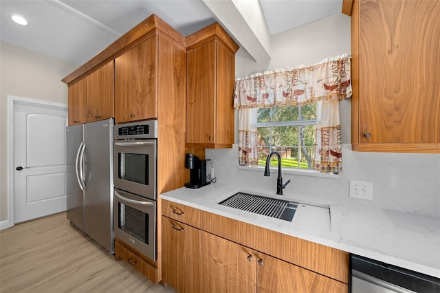 kitchen featuring stainless steel appliances, tasteful backsplash, light stone counters, and sink