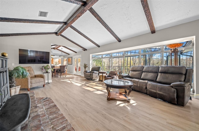 living room featuring a textured ceiling, light hardwood / wood-style flooring, and vaulted ceiling with beams