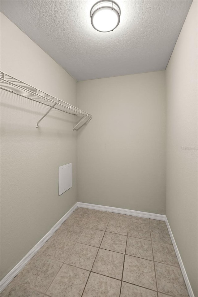 laundry area with a textured ceiling and light tile patterned floors