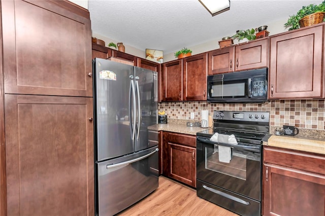 kitchen with a textured ceiling, light hardwood / wood-style floors, tasteful backsplash, and black appliances