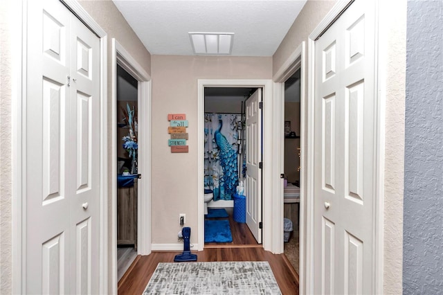 hall with a textured ceiling and dark hardwood / wood-style flooring