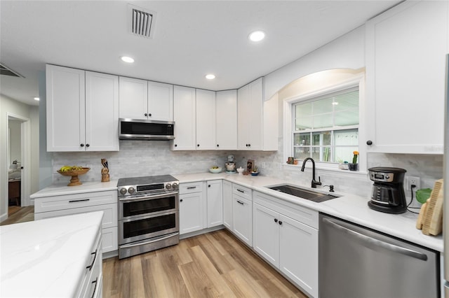 kitchen featuring sink, white cabinetry, appliances with stainless steel finishes, and light hardwood / wood-style flooring