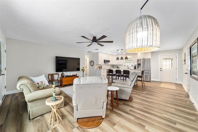 living room with ceiling fan and light wood-type flooring