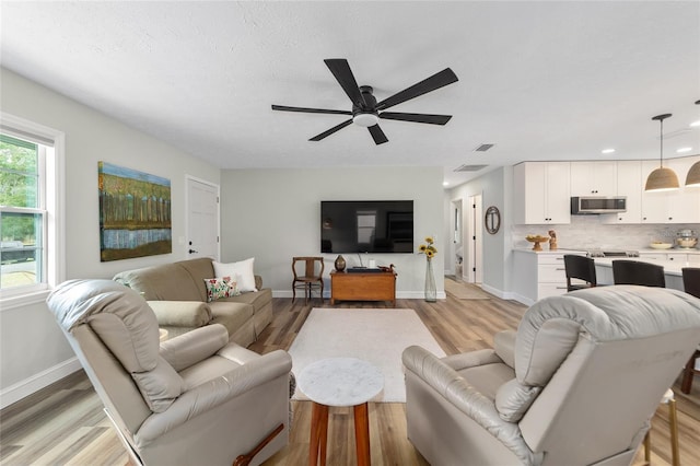 living room with ceiling fan and light wood-type flooring