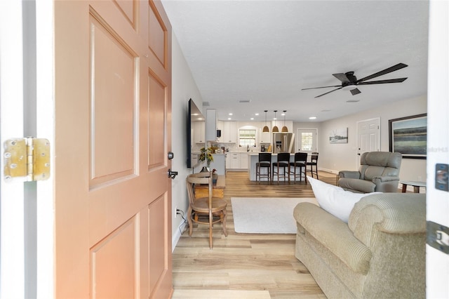 living room with ceiling fan and light hardwood / wood-style flooring