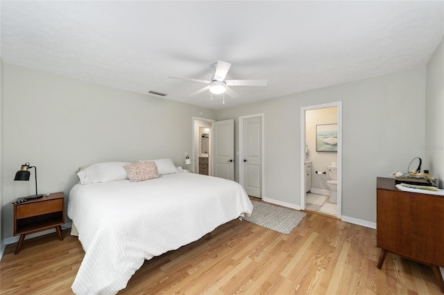 bedroom with ceiling fan, ensuite bathroom, and light hardwood / wood-style flooring