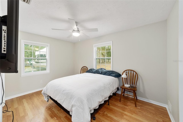 bedroom featuring ceiling fan, wood-type flooring, and multiple windows