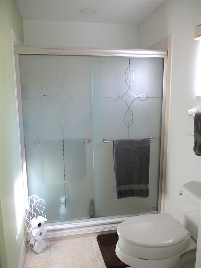 bathroom featuring toilet, tile patterned flooring, and a shower with shower door