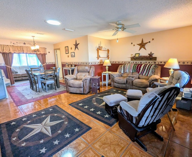 living room featuring tile patterned flooring, ceiling fan with notable chandelier, and a textured ceiling