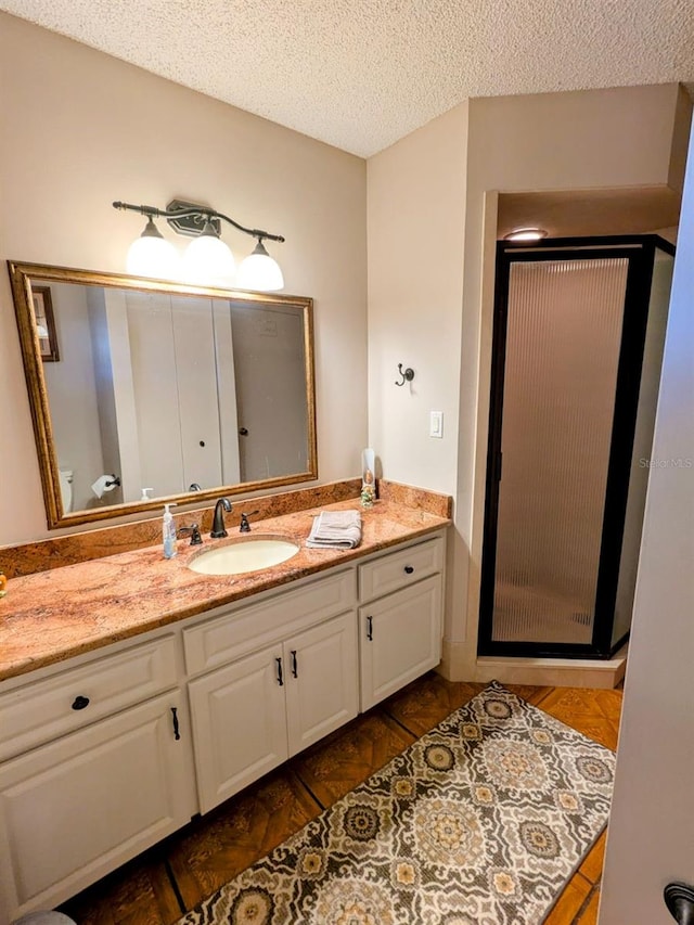 bathroom featuring hardwood / wood-style flooring, a textured ceiling, a shower with shower door, and vanity