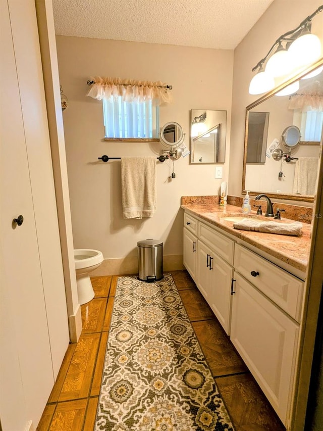 bathroom featuring vanity, toilet, and a textured ceiling