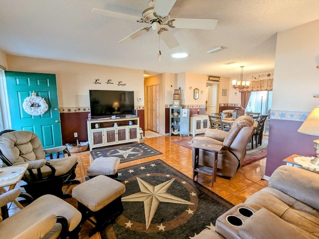 living room with ceiling fan with notable chandelier and a textured ceiling